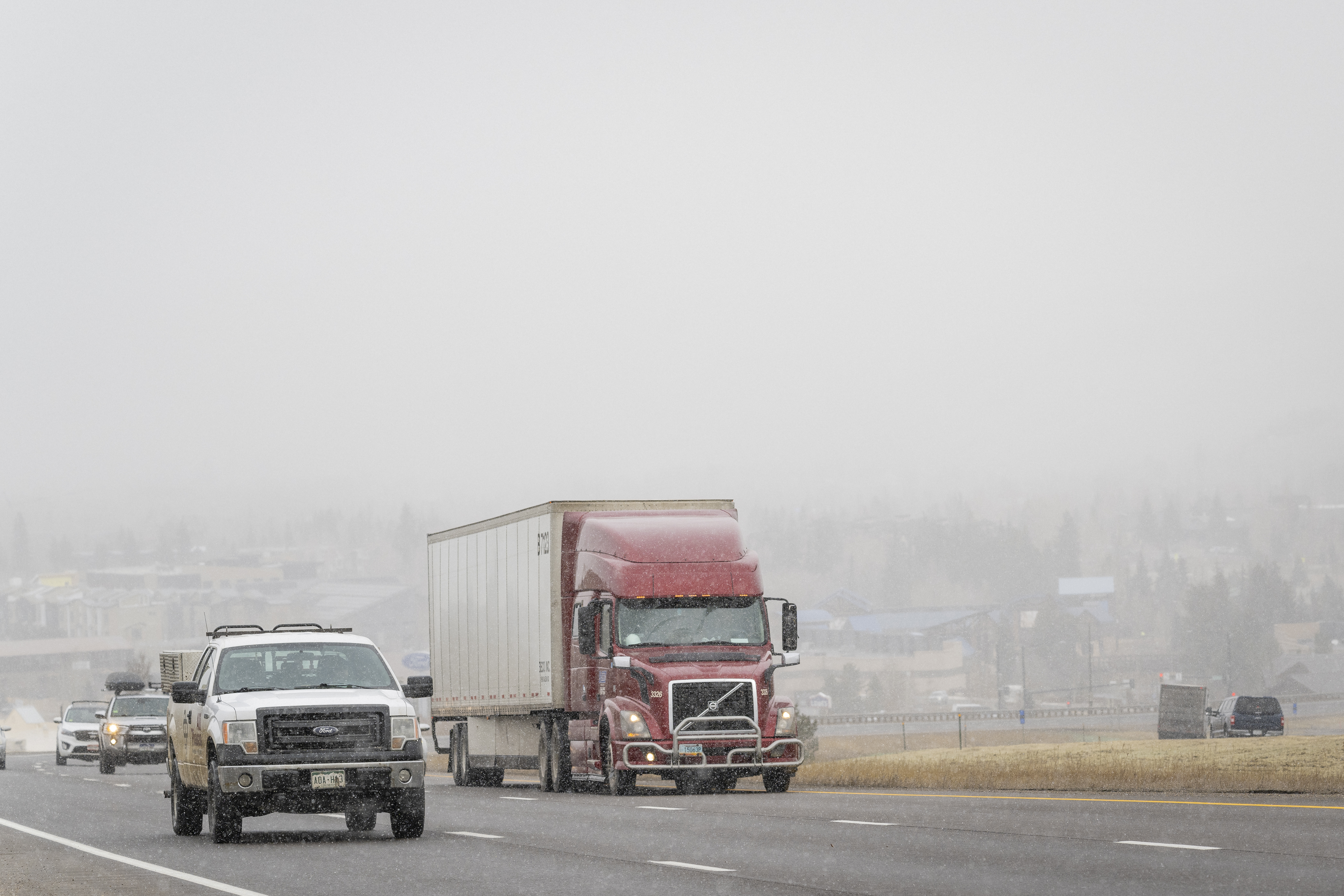 Semi truck and pick up driving down busy highway in the snow