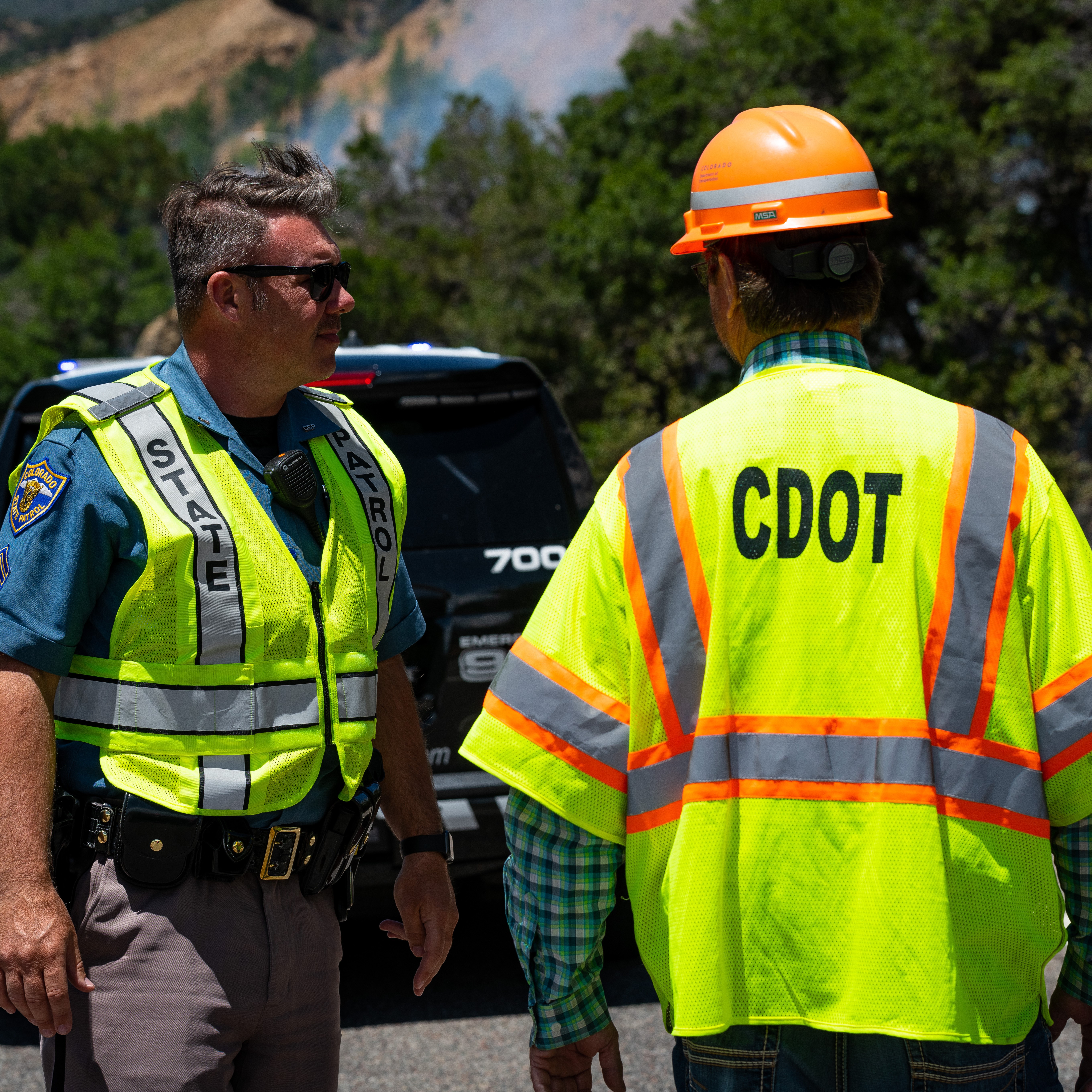 CDOT worker and Trooper on the side of the road in an ANSI vest.