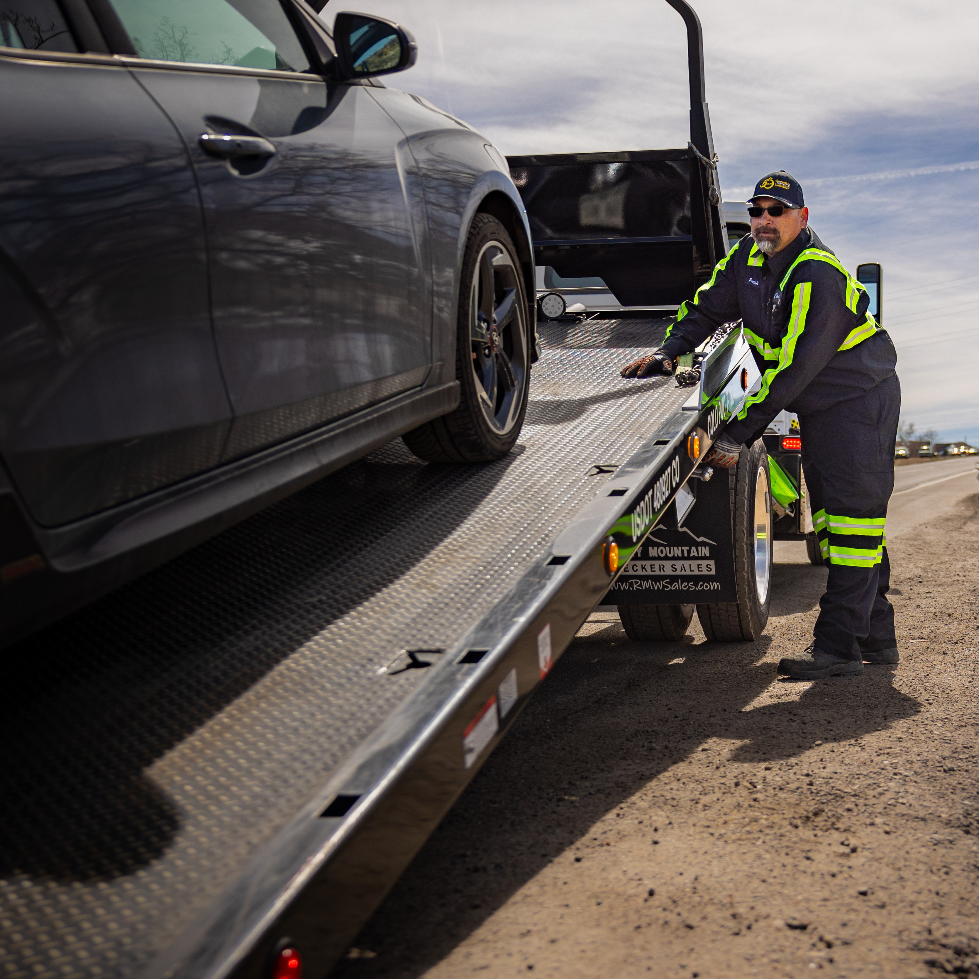 Tow truck driver loading vehicle onto tow truck.