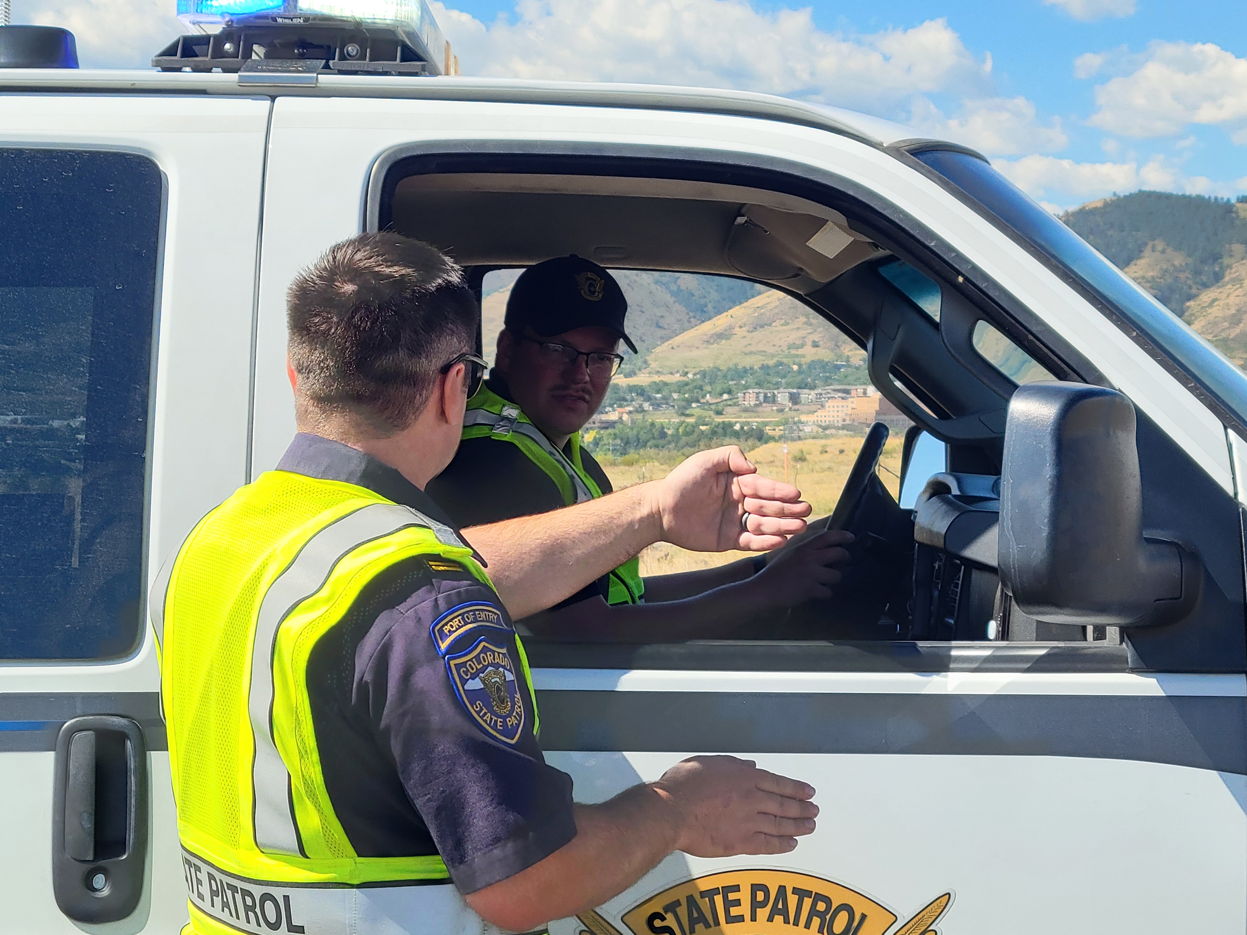 A cadet providing direction to another cadet sitting in a Port of Entry vehicle.